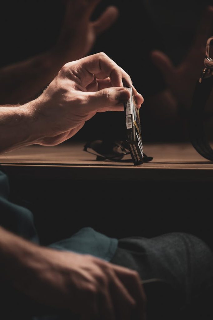 A hand holding a cigarette pack in moody, dim lighting, symbolizing habit and addiction.